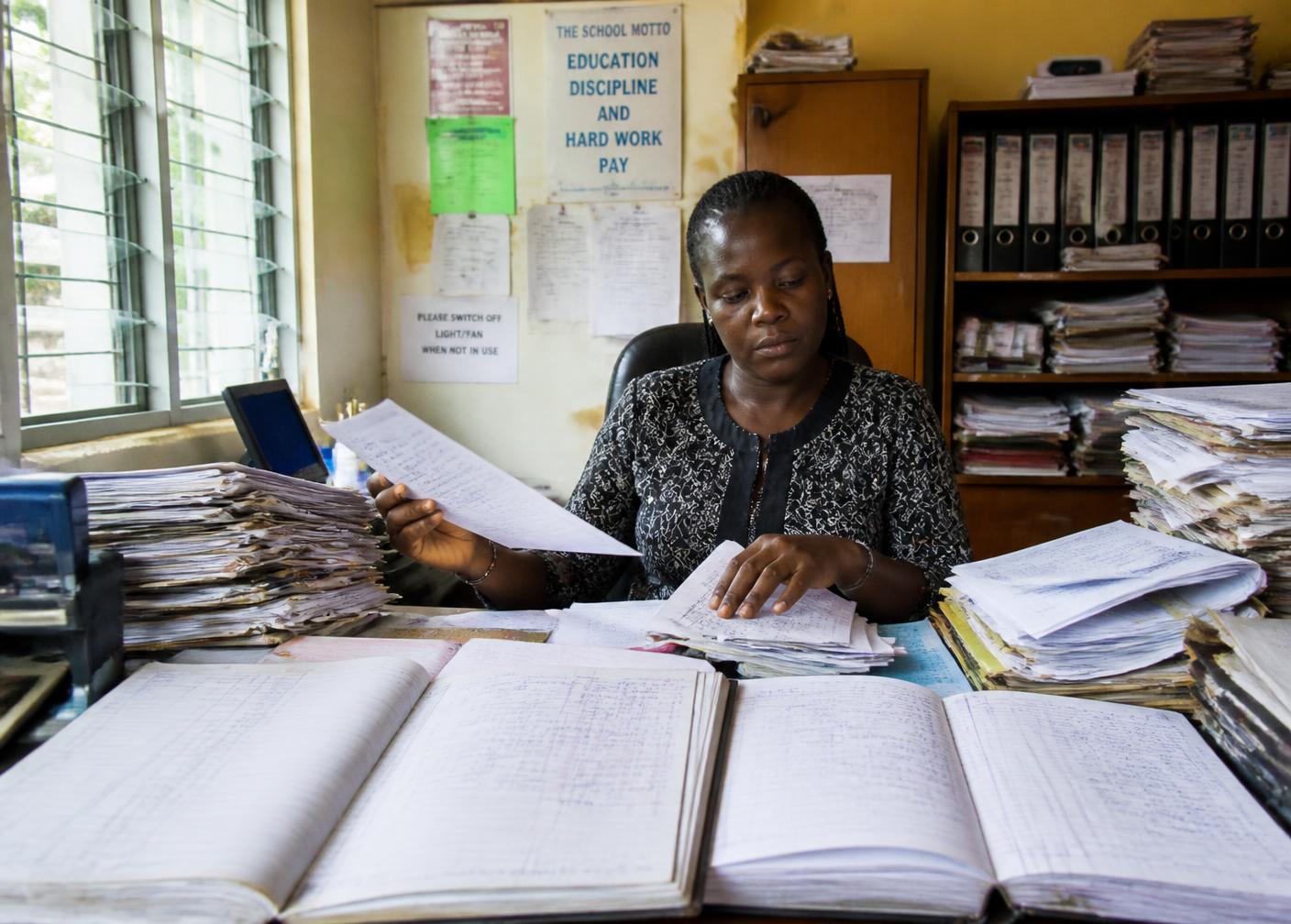 Bureau administratif scolaire submergé de registres et de dossiers papier